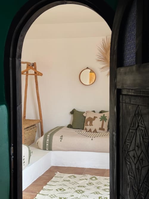 Arche menant à une chambre douillette au style bohème avec murs crème, détails en bois et coussins à motifs