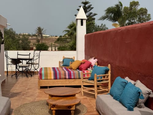 Suite sur le toit de l'hôtel Eucalyptus Ethnic à Essaouira avec mobilier en bois, coussins colorés et vue sur le jardin
