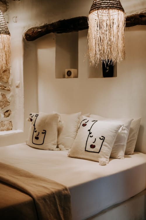Chambre cosy de l'hôtel Eucalyptus Ethnic à Essaouira avec coussins décoratifs visages et luminaires en fibres naturelles