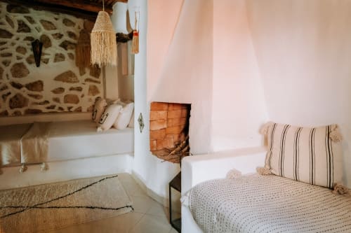 Chambre de la suite Beldi à l'hôtel Eucalyptus Ethnic Essaouira avec mur en pierre marocain traditionnel, lit intégré, coussins rayés