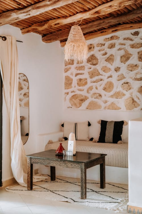 Suite Beldi de l'hôtel Eucalyptus Ethnic à Essaouira avec murs en pierre brute, poutres en bois et décor marocain traditionnel