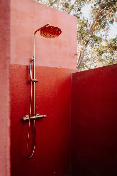 Douche extérieure de l'hôtel Eucalyptus Ethnic à Essaouira avec mur rouge et pomme de douche pluie