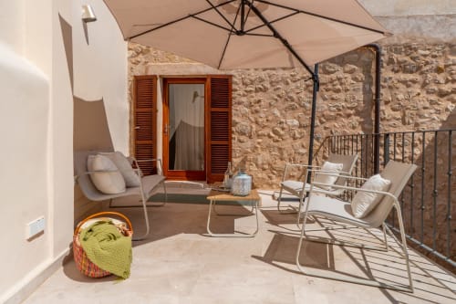 Terraza soleada en Massa Properties de Artà con tumbonas, sombrilla y arquitectura de piedra