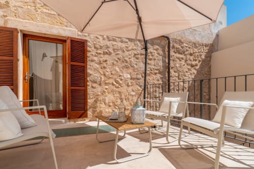 Terraza soleada en Massa Properties de Artà con muros de piedra, tumbonas, sombrilla y vistas al mar