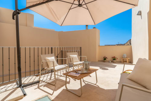 Soleada terraza en la azotea de Massa Properties en Artà con tumbonas, sombrilla y cielo azul despejado