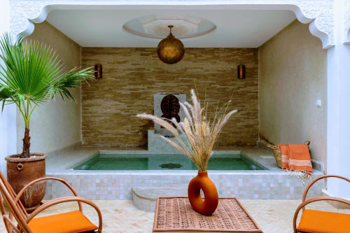 Spa Riad Dabachi Tala'lou avec piscine aux carreaux verts, murs en brique, palmiers et sièges orange à Marrakech