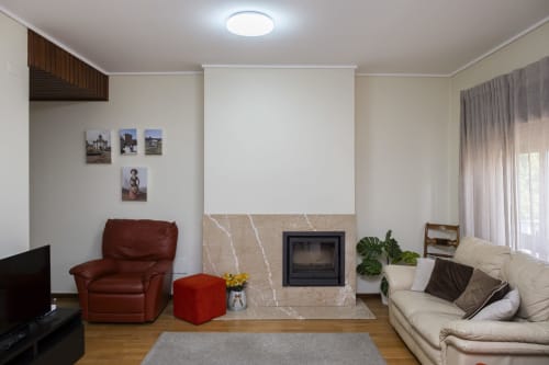 Sala de estar moderna com lareira, poltrona vermelha, sofá creme e vista para a cidade no RH Charming Apartments em Barcelos