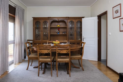 Sala de jantar elegante no Apartamento Charmoso RH, Barcelos com mesa de madeira, cadeiras e cristaleira com portas de vidro