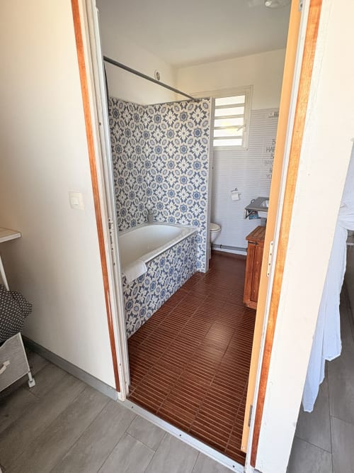 Salle de bains avec baignoire et cabine de douche à motifs bleus à l'Hôtel le soleil couchant à Saint-Pierre, Réunion