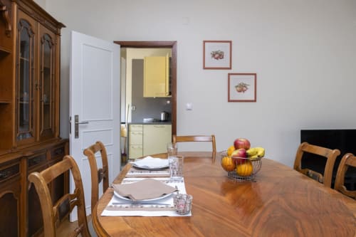 Sala de jantar do Apartamento Charming RH em Barcelos, com mesa de madeira, cadeiras, acesso à cozinha e fruteira decorativa