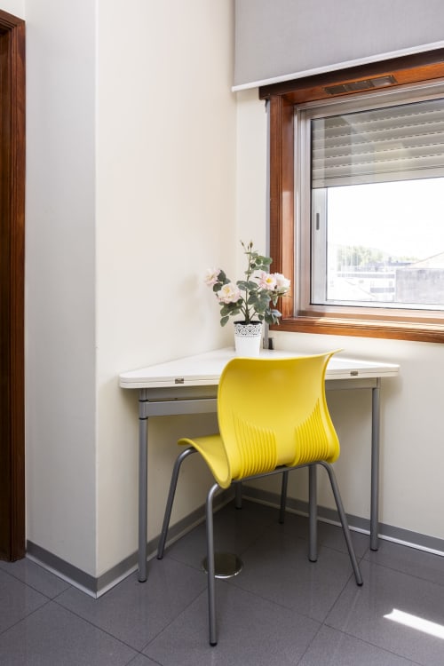 Espaço de trabalho iluminado com cadeira amarela em mesa branca perto da janela no Apartamento Charmoso RH, Barcelos