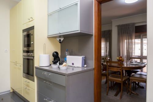 Cozinha moderna com armários amarelos e bancadas cinza se abrindo para área de refeições no Apartamento Encantador RH, Barcelos