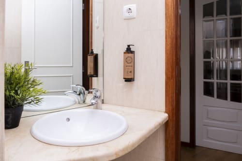 Pia de banheiro moderna com cuba de cerâmica branca, armário de madeira e artigos de higiene no Apartamento Charming RH em Barcelos
