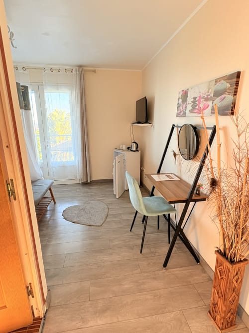Chambre moderne à l'Hôtel le soleil couchant avec bureau, chaise, TV et accès balcon surplombant Saint-Pierre, Réunion