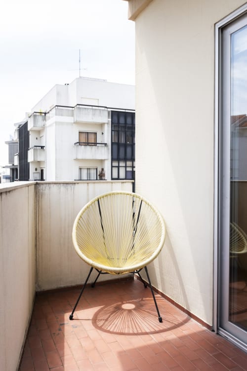 Cadeira redonda amarela no terraço do RH Charming Apartments em Barcelos, Portugal com vista para a cidade