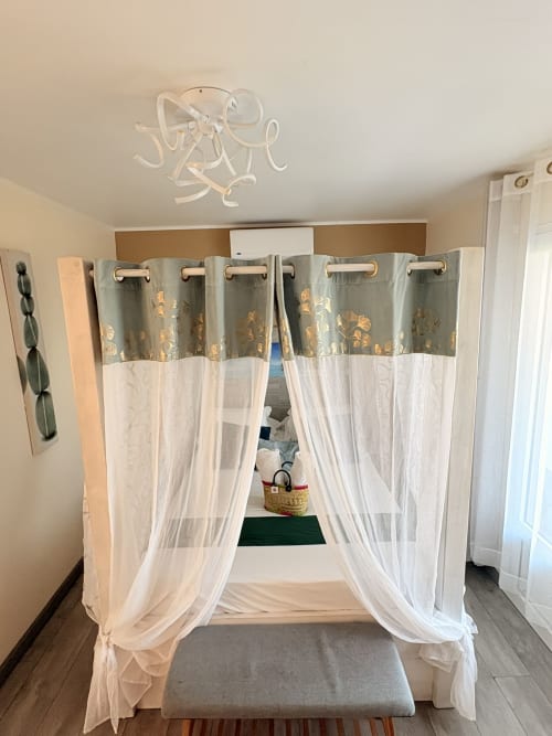 Lit à baldaquin avec voilages blancs et draperie à motifs dorés dans une chambre de l'hôtel St Pierre
