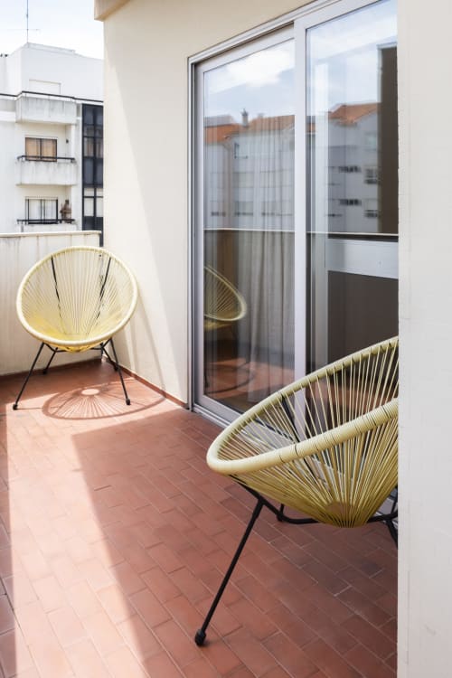 Varanda moderna no RH Charming Apartments em Barcelos com cadeiras tecidas amarelas e vista para a cidade