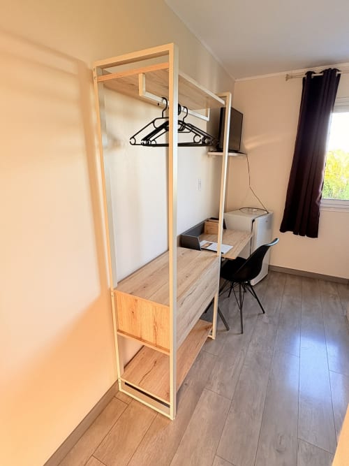 Armoire en bois moderne dans la chambre de l'Hôtel le soleil couchant à St Pierre, avec chaise de bureau et vue sur la fenêtre