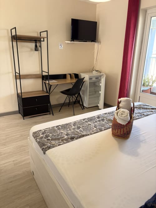 Chambre moderne à l'Hôtel le soleil couchant avec lit, bureau de travail, TV, rangements et accès balcon vue mer à St