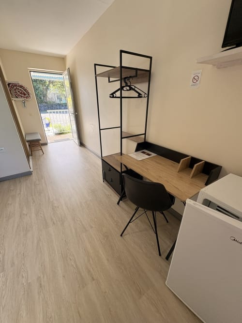 Chambre double moderne de l'Hôtel le soleil couchant avec bureau, chaise, armoire et accès à un balcon avec vue sur mer