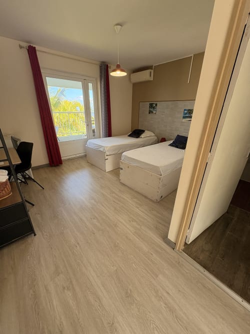 Spacieuse chambre double avec lits jumeaux, balcon vue mer, parquet et équipements modernes à l'Hôtel le soleil couchant