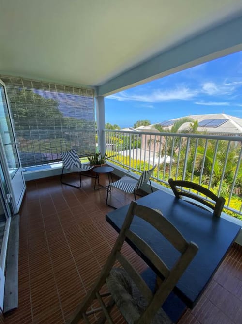 Balcon privé de l'Hôtel le soleil couchant à St Pierre avec vue mer, coin détente et palmiers