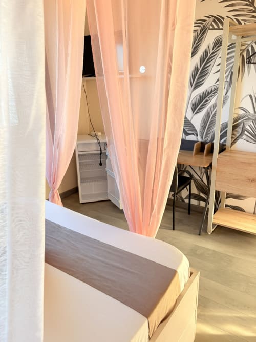 Chambre C5 de l'Hôtel le Soleil Couchant avec voilages roses, mobilier en bois et plantes en pot à Saint-Pierre, La Réunion