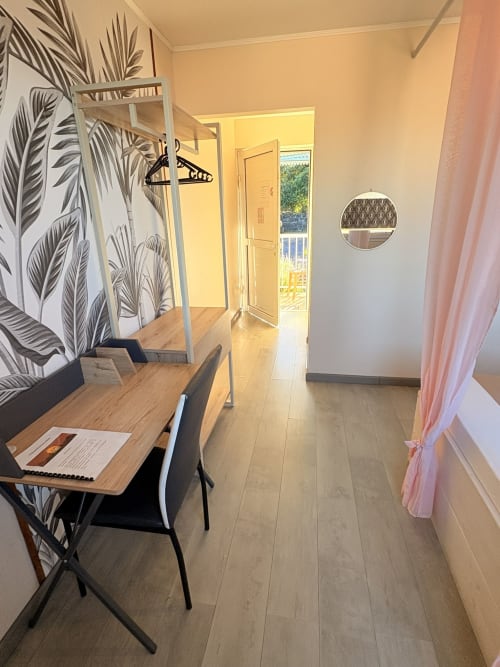 Chambre moderne à l'Hôtel le soleil couchant à St Pierre avec bureau en bois, décoration végétale et accès balcon vue jardin