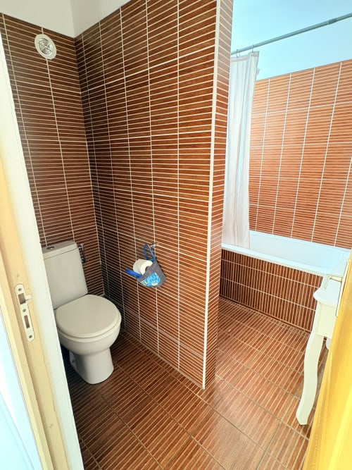 Salle de bain moderne de la chambre C5 de l'Hôtel le soleil couchant, avec carrelage marron, toilettes et douche à l'italienne vitrée