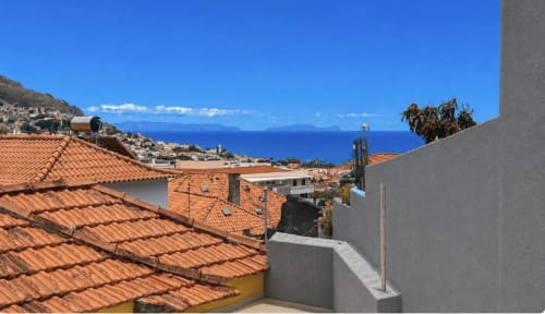 Villa em Funchal com terraço, telhados em terracota, vista para o oceano azul e montanhas ao longe
