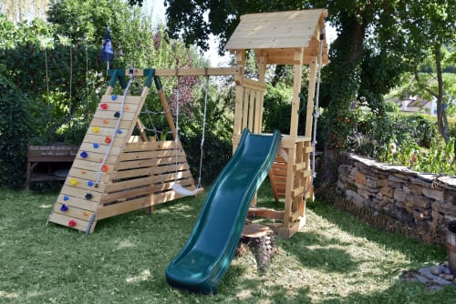 Parco giochi in legno con scivolo blu e parete d'arrampicata nel giardino di Gîte le Douglas, Lavigny