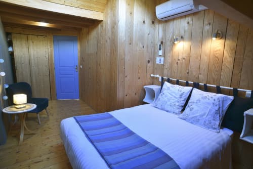 Camera da letto in cottage di legno moderno con accenti blu presso Gite Le Douglas a Lavigny, regione del Giura