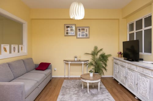 Sala de estar amarela vibrante no RH Charming Apartments em Braga com sofá cinza, TV, móveis brancos e planta em vaso
