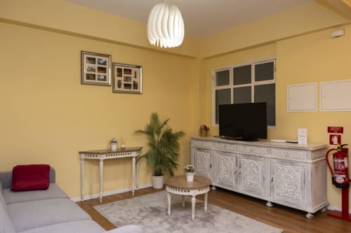 Sala de estar amarelo vibrante nos RH Charming Apartments em Braga com TV, móveis brancos e luminária pendente moderna