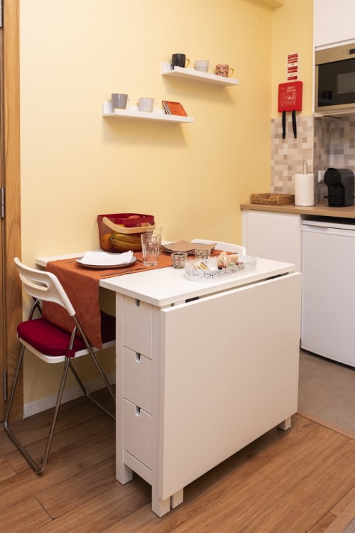 Compacto espaço de refeições no RH Charming Apartments em Braga com mesa de jantar, cadeira branca e paredes amarelas