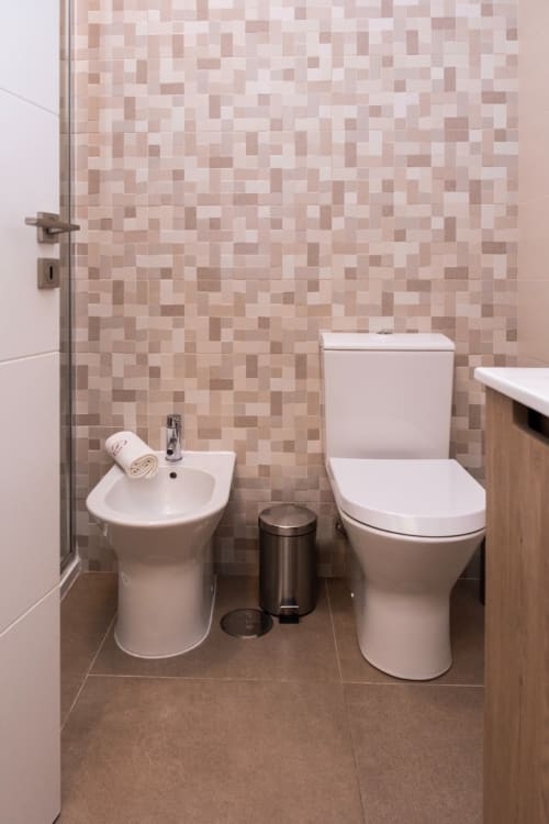 Banheiro moderno em RH Charming Apartments Braga com parede de azulejos em mosaico, vaso sanitário, bidê e pia