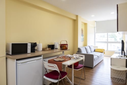 Moderno estúdio no RH Charming Apartments Braga com paredes amarelas, cozinha americana, sala de refeições, sofá e vista para a cidade