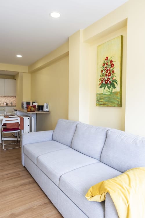 Sala de estar moderna no RH Charming Apartments em Braga com sofá cinza claro, paredes amarelas e arte floral