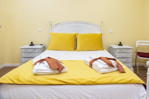 Quarto amarelo brilhante no RH Charming Apartments em Braga com camas gêmeas, cabeceira branca e toalhas acolhedoras