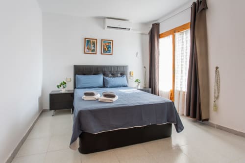 Dormitorio luminoso en Haus Holiday Homes en San Pedro del Pinatar con cama queen, ropa de cama azul, mesita de noche y acceso a patio