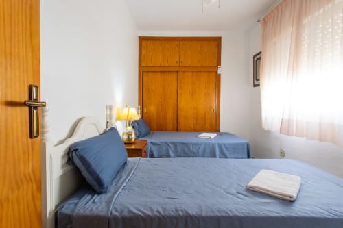 Dormitorio de Casa Bibaziz con camas gemelas, ropa de cama azul, armario de madera y ventana en San Pedro del Pinatar