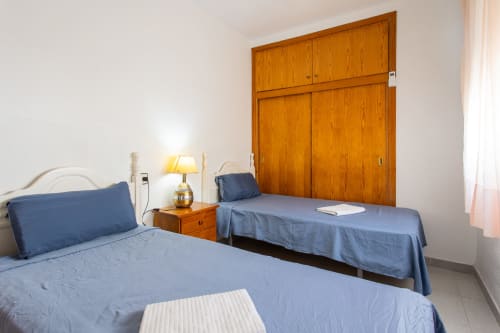 Dormitorio doble con ropa de cama azul en Haus Holiday Homes en San Pedro del Pinatar, armario de madera y mesilla de noche