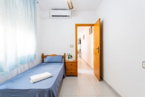 Dormitorio luminoso en Haus Holiday Homes, San Pedro del Pinatar, con cama de madera, ropa de cama azul y puerta abierta al baño