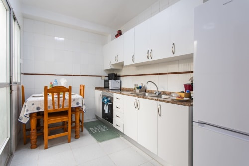 Cocina moderna con armarios blancos, encimera de granito y zona de comedor en Casa Bibaziz en San Pedro del Pinatar