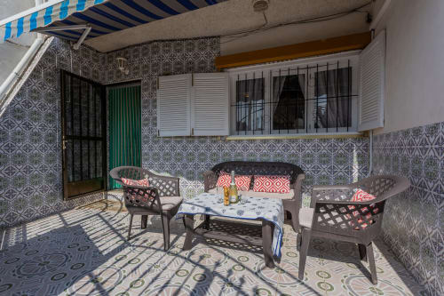 Acogedor patio de Haus Holiday Homes en San Pedro del Pinatar con asientos, toldo azul y decoración de azulejos tradicionales