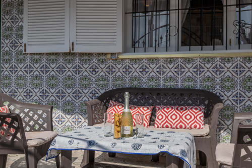 Patio exterior de Casa Bibaziz, San Pedro del Pinatar, con azulejos decorativos, mesa de comedor, botella de vino y detalles en rojo