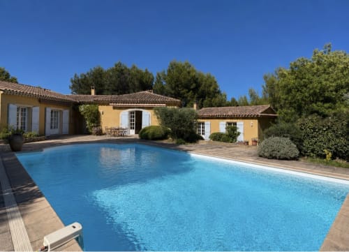 Piscine bleue de la Conciergerie Maurin à Arles avec bâtisses en pierre jaune et jardins méditerranéens