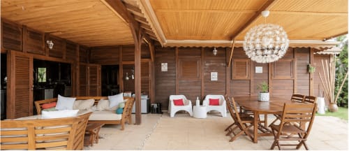 Terrasse couverte du Riviera BnB avec mobilier en bois, chaises blanches, table à manger et luminaires suspendus à Rivière Salée