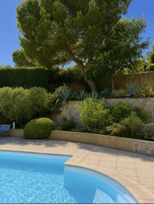 Piscine aux eaux turquoise, terrasse en pierre, jardins entretenus et arbres majestueux à la Conciergerie Maurin à Arles