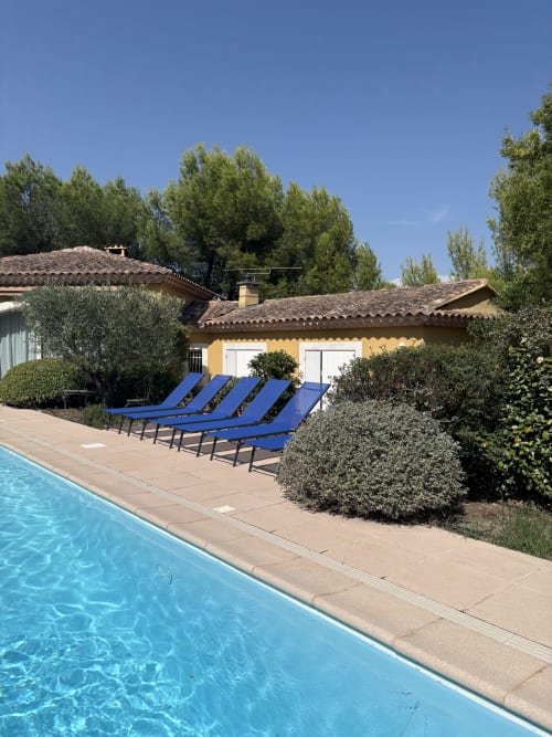 Piscine avec transats bleus à la Conciergerie Maurin à Arles, France, bâtiment jaune aux toits en terre cuite